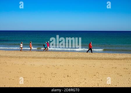 Menschen, die an den Sandstränden spazieren gehen, Gesichtsmasken tragen, in La Mata, Torrevieja, Costa Blanca, Spanien, Winter, Wintersonne, Reiseziel Stockfoto