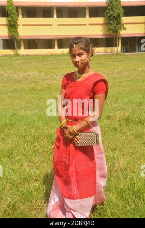 Nahaufnahme eines indischen bengalischen Teenager-Mädchen mit langen dunklen Haaren tragen traditionellen roten Sari mit Armreifen Handtasche und Schmuck Nasenring, Ohrring. Stockfoto