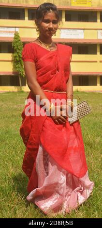 Nahaufnahme eines indischen bengalischen Teenager-Mädchen mit langen dunklen Haaren tragen traditionellen roten Sari mit Armreifen Handtasche und Schmuck Nasenring, Ohrring. Stockfoto