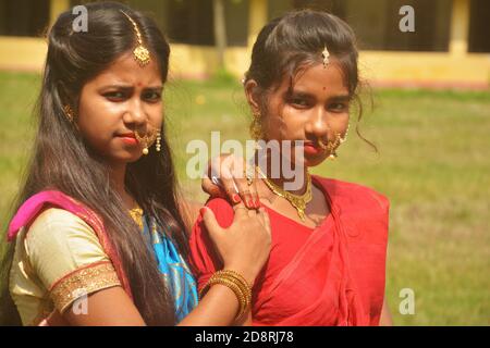 Nahaufnahme von zwei Schwestern tragen traditionelle Saree und Schmuck wie Nasenringe Ohrringe maang tika Armreifen während Durga Puja, selektive Fokussierung Stockfoto