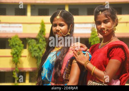 Nahaufnahme von zwei Schwestern tragen traditionelle Saree und Schmuck wie Nasenringe Ohrringe maang tika Armreifen während Durga Puja, selektive Fokussierung Stockfoto