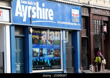 Ayr, Ayrshire, Schottland, Vereinigtes Königreich . Ehrliche Straßenfotografie rund um Ayr. Wona mit Einkaufstaschen, die müde aussassen, als sie an der Bushaltestelle wartete Stockfoto