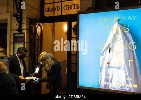 Während Premierminister Boris Johnson während der zweiten Welle der Pandemie eine landesweite Sperrung des zweiten Coronavirus ankündigt, überprüfen Mitarbeiter die Kundentickets vor dem Apollo Theater auf der Shaftesbury Avenue, wo Adam Kays medizinische Komödie "This is Going to Hurt" am 31. Oktober 2020 in London, England, spielt. Aber Geschäfte wie Theater müssen ab Donnerstag wieder geschlossen werden, und zwar für einen Zeitraum von mindestens einem Monat. Stockfoto