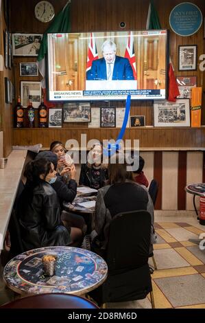 Auf einem Fernsehbildschirm in Bar Italia, dem berühmten italienischen Café in Soho, spricht Premierminister Boris Johnson Großbritannien im Live-Fernsehen an, um eine zweite landesweite Sperre während der zweiten Welle der Coronavirus-Pandemie am 31. Oktober 2020 in London, England, anzukündigen. Unternehmen wie die Bar Italia müssen bis auf Takeaways wieder geschlossen werden, und zwar ab Mitternacht am Donnerstag für einen Zeitraum von einem Monat. Stockfoto