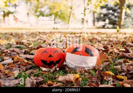 Zwei Herbstkürbisse krank COVID19 und gesund im Herbst Gras.Halloween Stockfoto