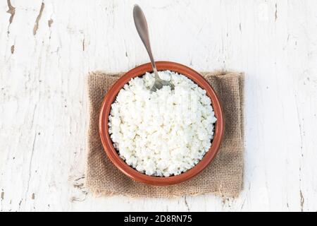 Hausgemachter Hüttenkäse in einer Keramikschale auf weißem alten Holztisch. Gesunde Ernährung. Frische Milchprodukte. Draufsicht Stockfoto