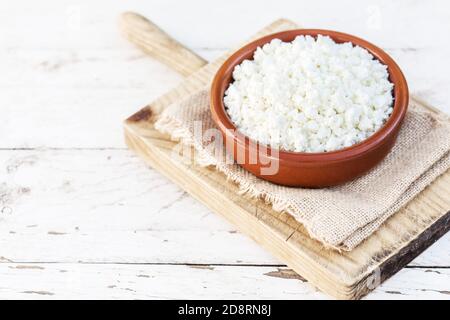 Hausgemachter Hüttenkäse in einer Keramikschale auf weißem alten Holztisch. Gesunde Ernährung. Frische Milchprodukte. Draufsicht Stockfoto