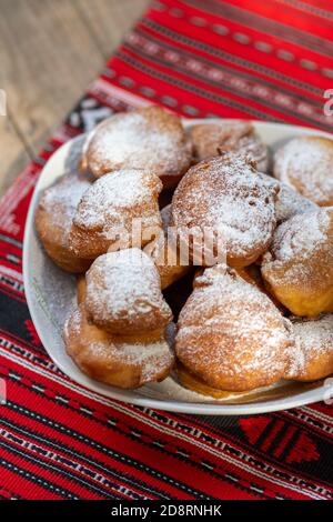 rumänische Mini-Donuts auf einem Teller auf rotem traditionellen Tuch Stockfoto