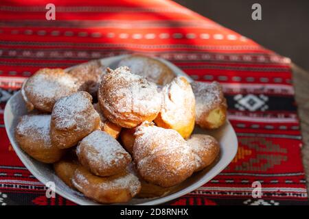 rumänische Mini-Donuts auf einem Teller auf rotem traditionellen Tuch Stockfoto