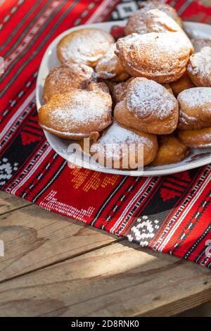 rumänische Mini-Donuts auf einem Teller auf rotem traditionellen Tuch Stockfoto