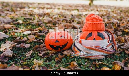 Kürbis liegt auf dem Gras im Park in einem orangen Hut und Schal, krank COVID19 Stockfoto