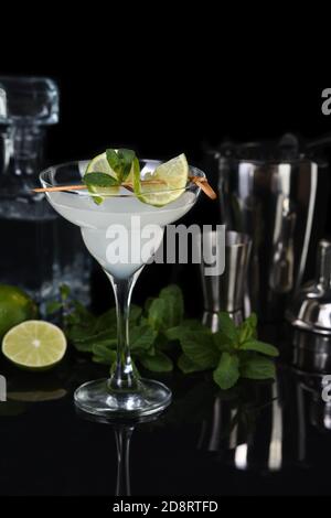 Tequila, Zitruslikör, Limettensaft - das ist ein Margarita-Cocktail. Ein Kalkstein mit einem Zweig Minze schmückt ein Glas. Dunkles, launisch gelauntes Essen Stockfoto