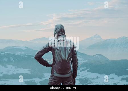 Person steht vor einer Bergkette und blickt ins Tal. Stockfoto