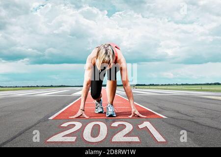 Die Läuferin wartet auf ihren Start auf einer Landebahn am Flughafen. Im Vordergrund symbolisiert das gemalte Datum 2021 das Jahr. Stockfoto