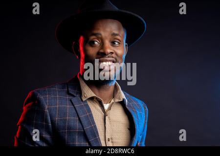 Afroamerikanischer Mann lächelt und schaut auf die Kamera auf schwarzem Hintergrund, Nahaufnahme Stockfoto