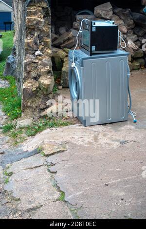 Alte Waschmaschine und Mikrowelle vor dem Haus warten auf Abholung Durch Recycling-Van Stockfoto