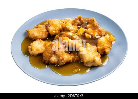 chinesische Küche: Schweinefleisch in Orangensauce (In Scheiben geschnittenes Schweinefilet in Teig mit Orangensauce und gebraten Garniert mit Koriander) auf blauer Platte isoliert o Stockfoto