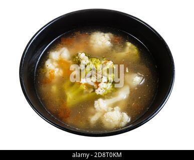 Suppe mit stelline (italienische Pasta) und Gemüse (Blumenkohl, Brokkoli, etc.) in schwarzer Schüssel isoliert auf weißem Hintergrund Stockfoto