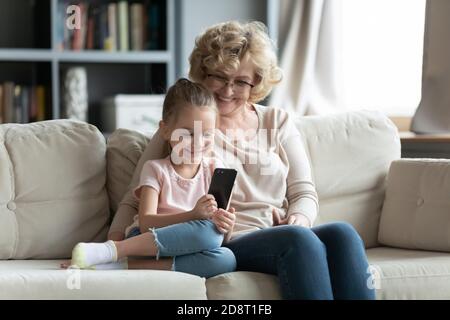 Lächelnd verschiedene weibliche Generationen Familie spielen mobile Spiele. Stockfoto