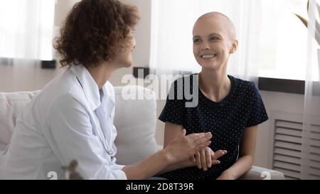 Nahaufnahme fürsorglicher Arzt hält lächelnde haarlose Frau Hand, Unterstützung Stockfoto