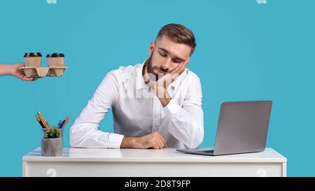 Schöner Geschäftsmann müde von Computer Arbeit schlafen an seinem Schreibtisch auf blauem Studio Hintergrund, Panorama Stockfoto