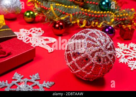 Rote Weihnachtskugel für Weihnachtsbaum und Geschenke auf rotem Hintergrund. Schönes Weihnachtsfoto 2021 Stockfoto