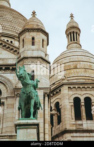 Vertikale Aufnahme der Basilika Sacre Coeur mit der Statue Jeanne d'Arc in Paris, Montmartre, Frankreich Stockfoto