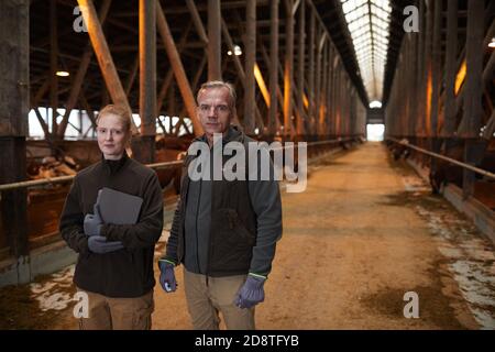 Waist up Porträt von Vater und Tochter stehen in Scheune und Blick auf die Kamera während der Arbeit auf Familienfarm, kopieren Raum Stockfoto