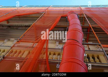 Abfallschacht oder Schuttschacht in roter Farbe an einer Fassade eines historischen Gebäudes in Rekonstruktion zur Müllentsorgung. Das Haus ist überdacht. Stockfoto