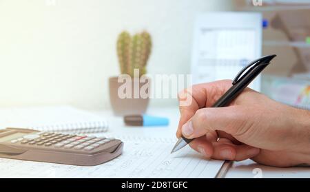 Der Student löst mathematische Formeln. Der Mensch schreibt mit einem Stift in ein Notizbuch. Hausaufgaben. Notizen in einem Notizbuch. Stockfoto