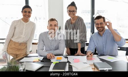 Erfolgreiche junge, vielfältige internationale Firmenmitarbeiter versammelten sich am Tisch. Stockfoto