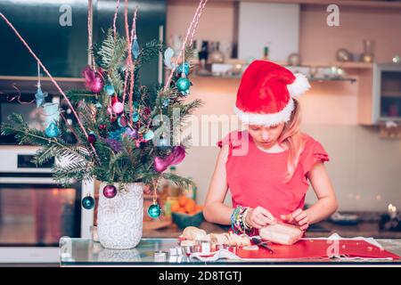 Schöne blonde Mädchen Vorbereitung Süßigkeiten in weihnachtsatmosphäre in der Wohnküche Stockfoto