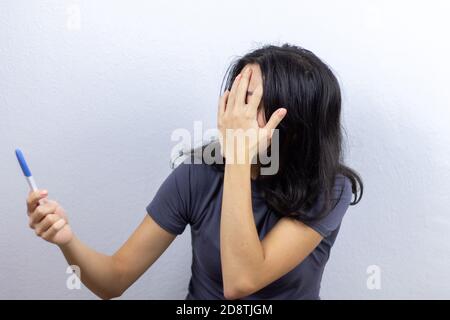 Mädchen mit Schwangerschaftstest auf weißem Hintergrund Stockfoto