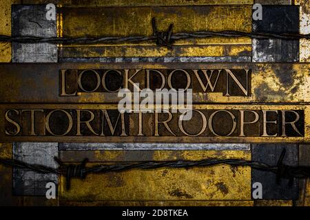 Lockdown Stormtrooper Textnachricht auf texturiertem Grunge Kupfer und vintage Gold Hintergrund umgeben von Stacheldraht Stockfoto