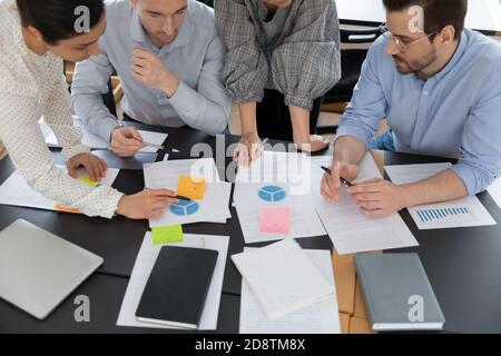 Draufsicht konzentrierte junge ernsthafte multirassische Teamkollegen, die Papierkram machen. Stockfoto