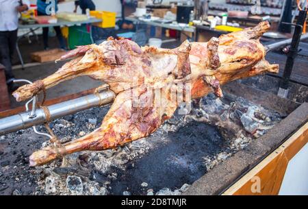 Kochen Lammkarkasse auf einem Spieß auf dem offenen Feuer des Grills auf dem Straßenmarkt geröstet. Traditionelle serbische Braten Lamm oder Schweinefleisch Grill Stockfoto