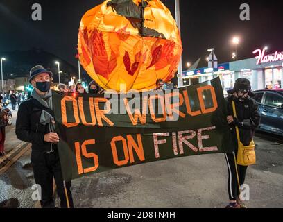 Hastings, Großbritannien. Oktober 2020. Extinction Rebellion Halloween Protest und März. Der lebhafte marsch verließ die Altstadt einmal dunkel, und schloss laute Samba Trommler, Skelette, hell erleuchtete Fahrräder, eine Welt im Feuer Bildnis, Feuer Fackeln und endete mit Rauchbomben. Die Straßen wurden durch 10M Banner blockiert, damit der marsch sicher Straßen überqueren konnte. Der Protest forderte sofortige und sinnvolle Maßnahmen der Regierung, um den Herausforderungen einer Klimanotlage zu begegnen. Veranstaltet von Extinction Rebellion Hastings / St. Leonards und Extinction Rebellion Southeast UK. Quelle: Stephen Bell/Alamy Stockfoto