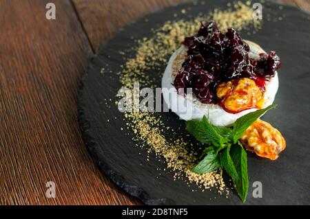 Frisch gebackener gegrillter Camembert mit Cranberry-Sauce, Kräutern und karamellisierten Walnüssen aus nächster Nähe Stockfoto