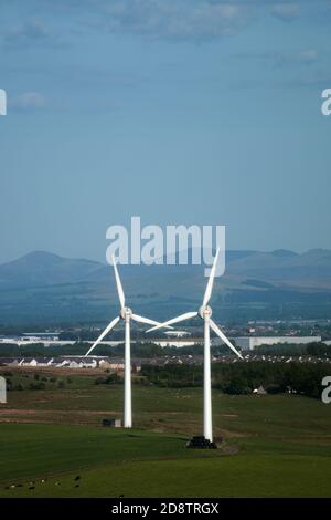 Windmühlen auf dem Feld auf dem Hintergrund von Dorf und Berge. West Lothian, Schottland, Großbritannien Stockfoto