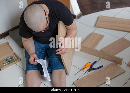 Bärtiger Kerl sammelt Möbel in einer neuen Wohnung. Nahaufnahme Stockfoto