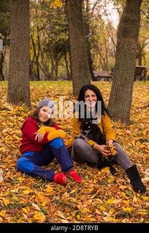 Glückliche Mutter und ihr Sohn sitzen im Herbst Blätter in parken Stockfoto