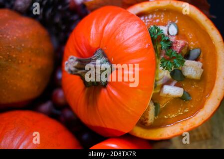 Kürbiscremesuppe. Vegetarische Herbst-Kürbis-Karottensuppe in einem hohlen Kürbis mit Sahne, Kürbiskernen, Petersilie und Croutons. Herbst, Danksagung Stockfoto