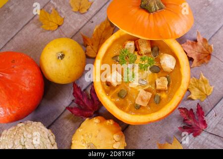 Kürbiscremesuppe. Vegetarische Herbst-Kürbis-Karottensuppe in einem hohlen Kürbis mit Sahne, Kürbiskernen, Petersilie und Croutons. Herbst, Danksagung Stockfoto