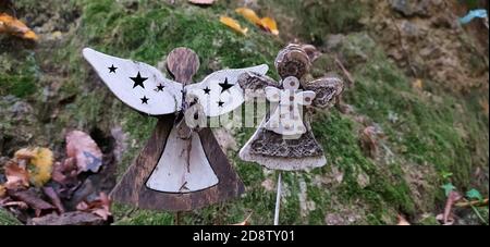 Schöne Engel Dekorationen mit Flügeln auf der Rückseite im Vintage-Garten. Engelsstatue gegen grünen moosigen Stein. Innen von verlassenen Garten mit Engel stat Stockfoto