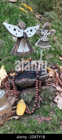 Schöne Engel Dekorationen mit Flügeln auf der Rückseite im Vintage-Garten. Engelsstatue gegen grünen moosigen Stein. Innen von verlassenen Garten mit Engel stat Stockfoto