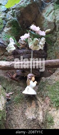 Schöne Engel Dekorationen mit Flügeln auf der Rückseite im Vintage-Garten. Engelsstatue gegen grünen moosigen Stein. Innen von verlassenen Garten mit Engel stat Stockfoto