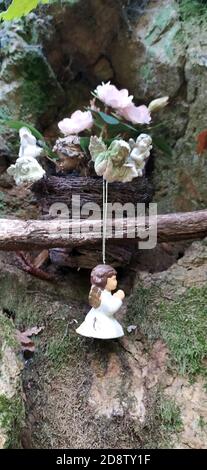 Schöne Engel Dekorationen mit Flügeln auf der Rückseite im Vintage-Garten. Engelsstatue gegen grünen moosigen Stein. Innen von verlassenen Garten mit Engel stat Stockfoto