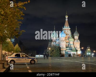 Auf dem Platz vor der Basilius-Kathedrale ist ein Polizeiauto im Einsatz.am späten Abend in Moskau, im Herzen Russlands - auf dem Roten Platz, passieren Menschen wie Schatten die schlafende jahrhundertealte Geschichte des Landes. Stockfoto