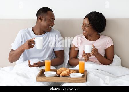 Liebende afroamerikanische Familie, die im Bett gefrühstückt hat Stockfoto