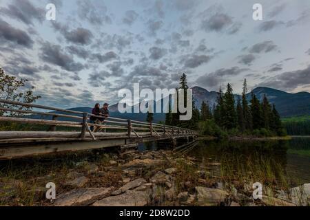 Mann und Frau stehen auf der Brücke am Pyramid Lake in Jasper, Alberta, Kanada Stockfoto